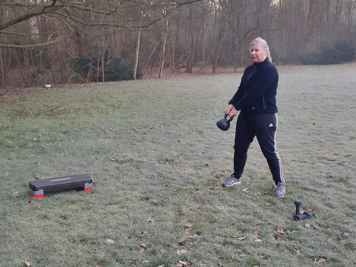 Iemand traint met een kettlebell op een berijpt grasveld