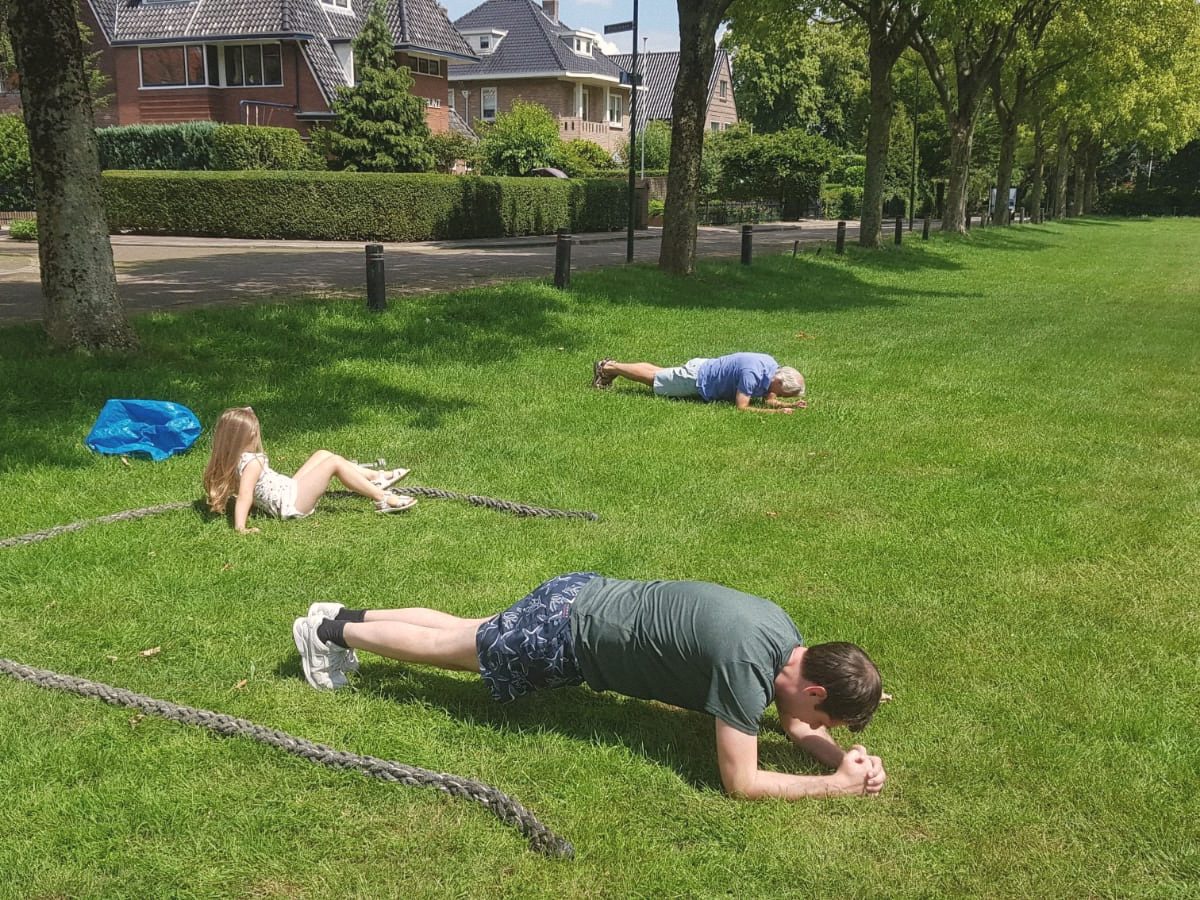 Twee mensen houden een plank vast op het gras in een park